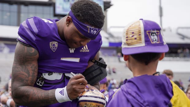 The graduated Richard Newton autographs a mini helmet for a young fan.